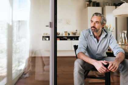 pensive bearded business man sitting on chair looking out of the window